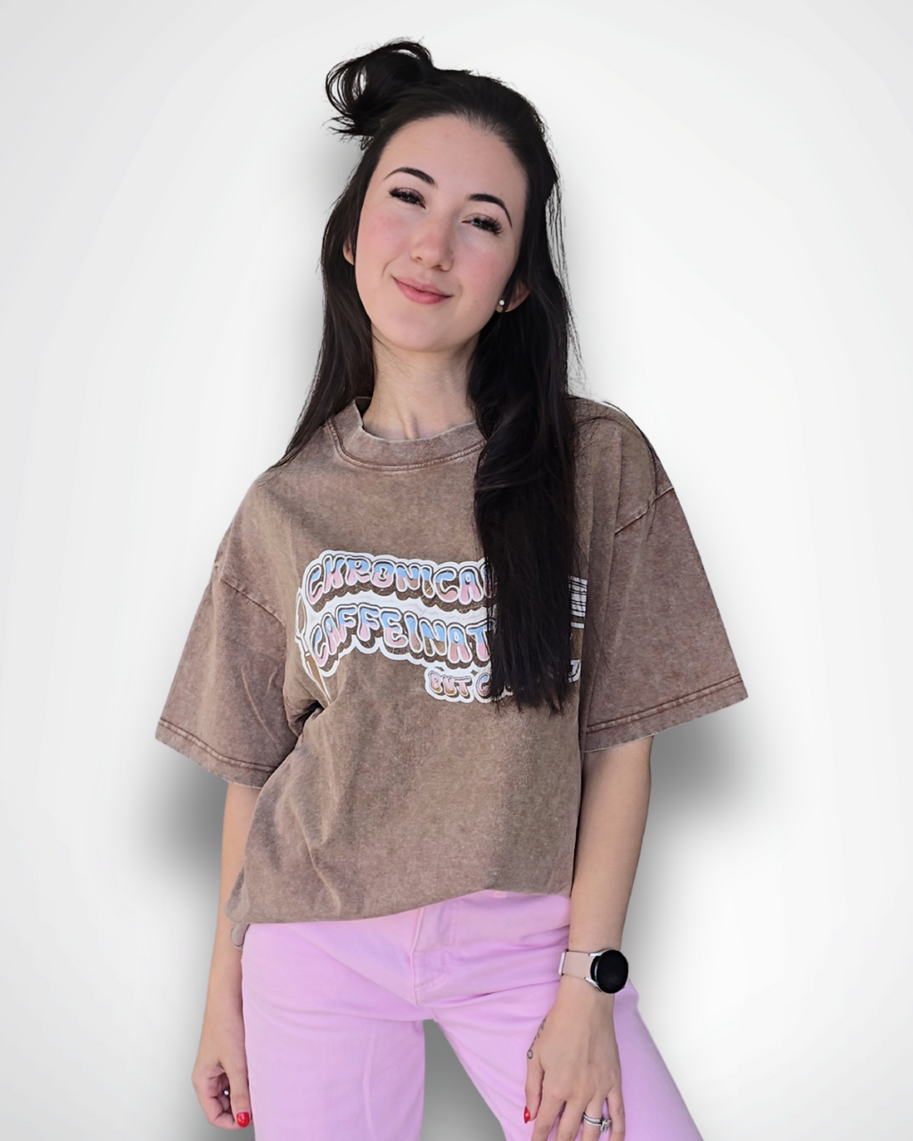 Woman wearing a brown oversized t-shirt with a graphic design and pink pants on a white background