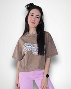 Woman wearing a brown oversized t-shirt with a graphic design and pink pants on a white background
