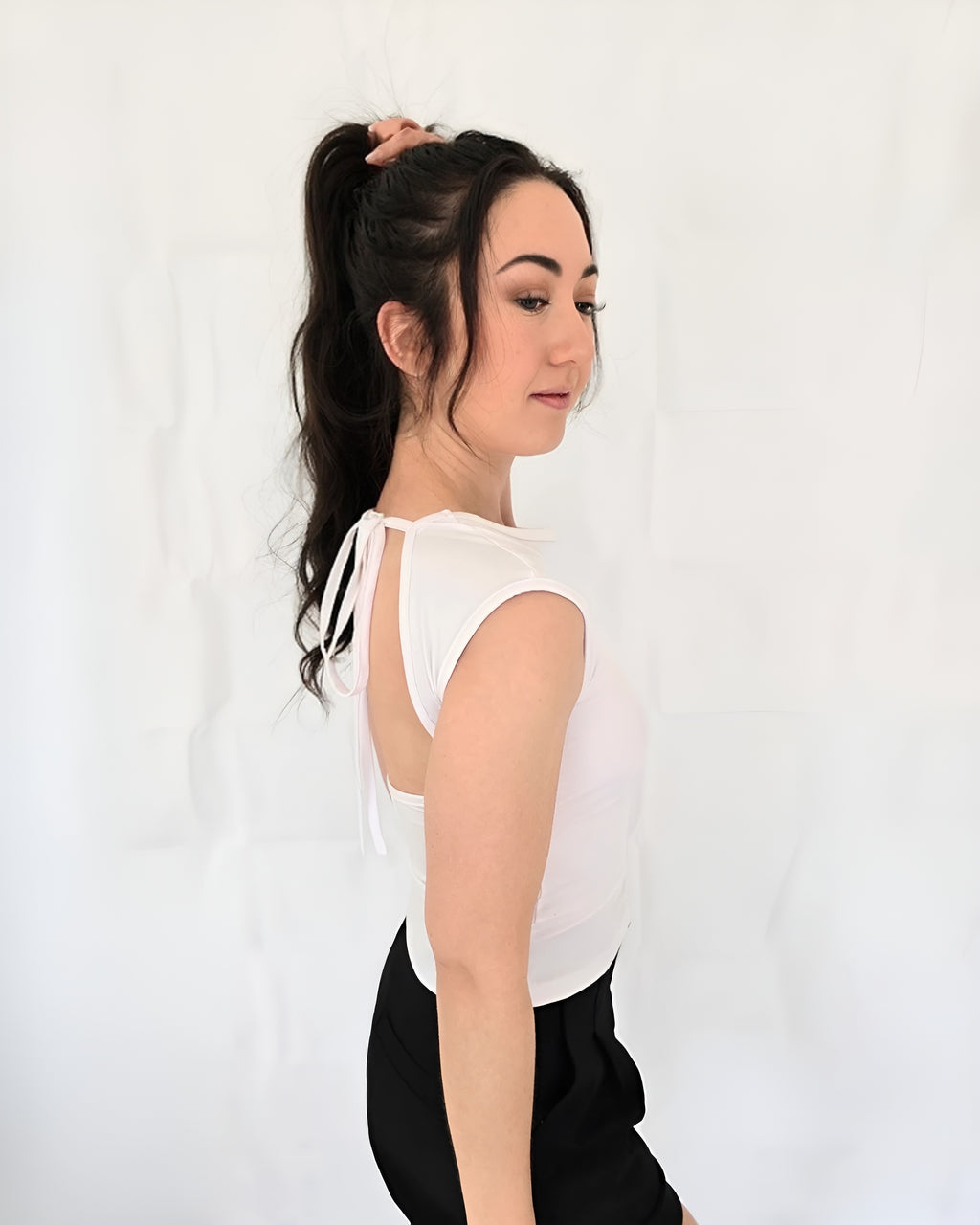 Woman wearing a white sleeveless top with a cut out design tie up halter neck low back