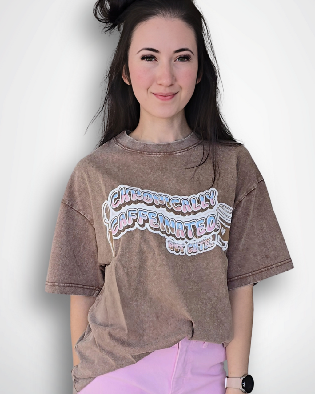 Person wearing a brown oversized t-shirt with text and pink pants on a white background