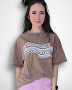 Person wearing a brown oversized t-shirt with text and pink pants on a white background