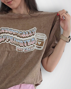 Woman holding a brown oversized t-shirt with graphic design on a plain background